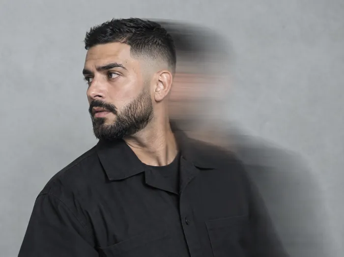 Daan, a barber with a tight skin fade and black beard, turning his head with a motion-blur trail
